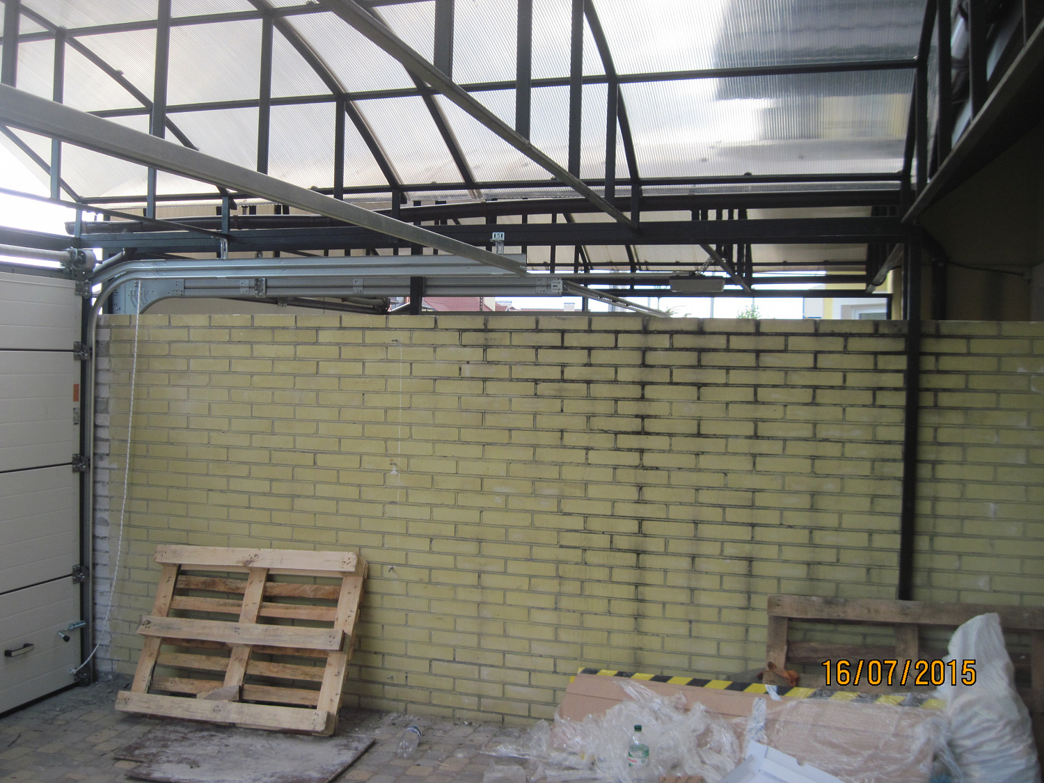 Ворота секционные Алютех под металлическим навесом. Въезд во двор S-гофр RAL 8014.