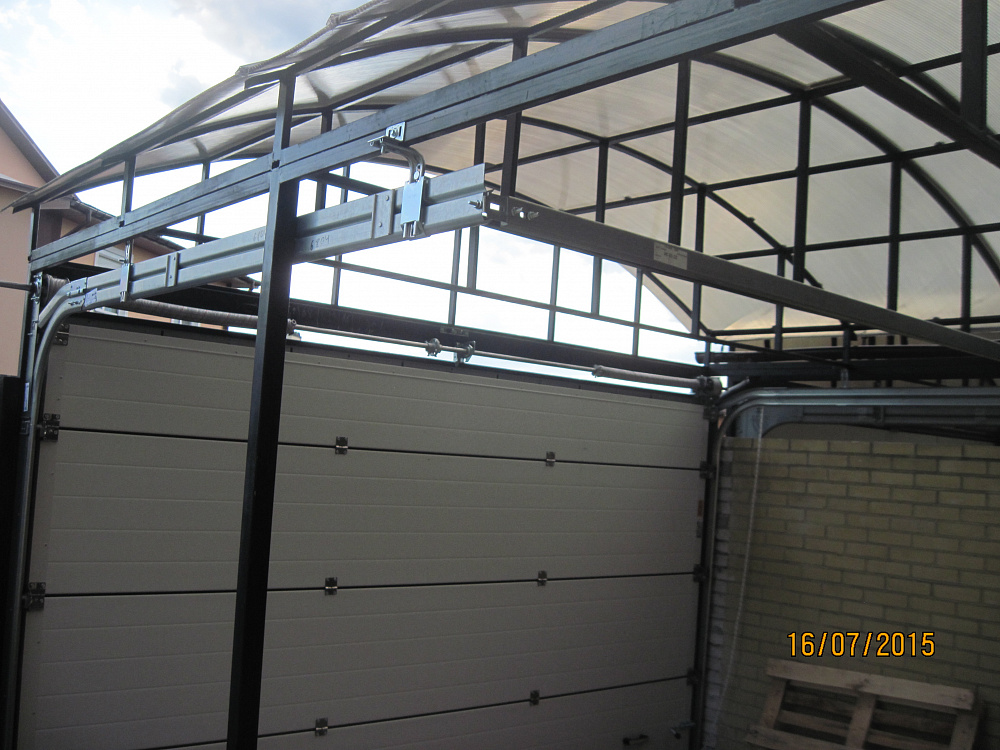 Ворота секционные Алютех под металлическим навесом. Въезд во двор S-гофр RAL 8014.