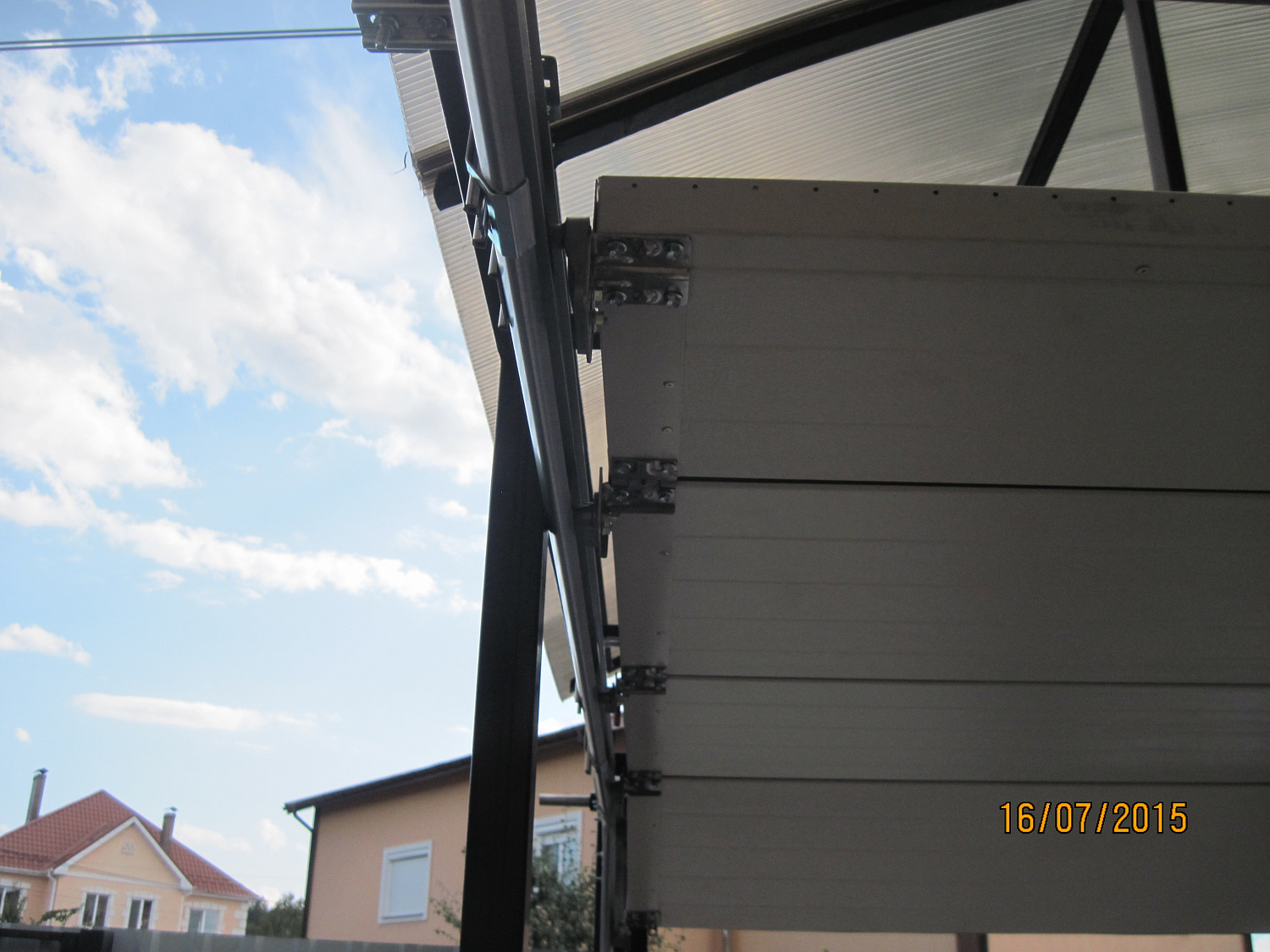 Ворота секционные Алютех под металлическим навесом. Въезд во двор S-гофр RAL 8014.